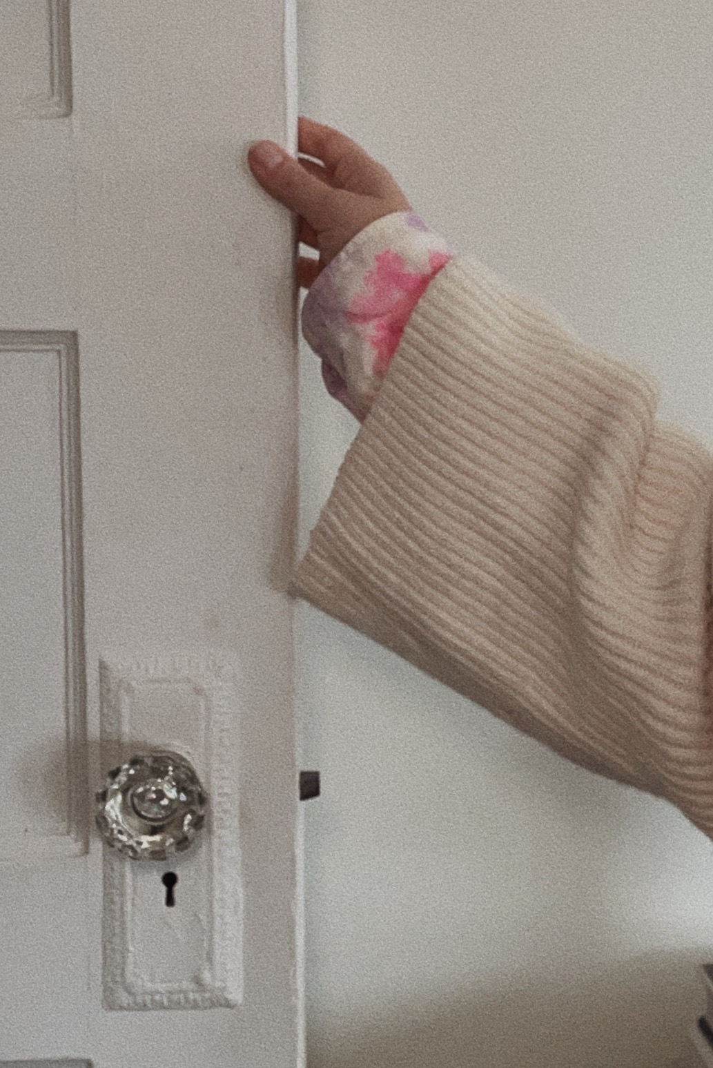 close up image of tie dye sleeve holding door with antique door knob