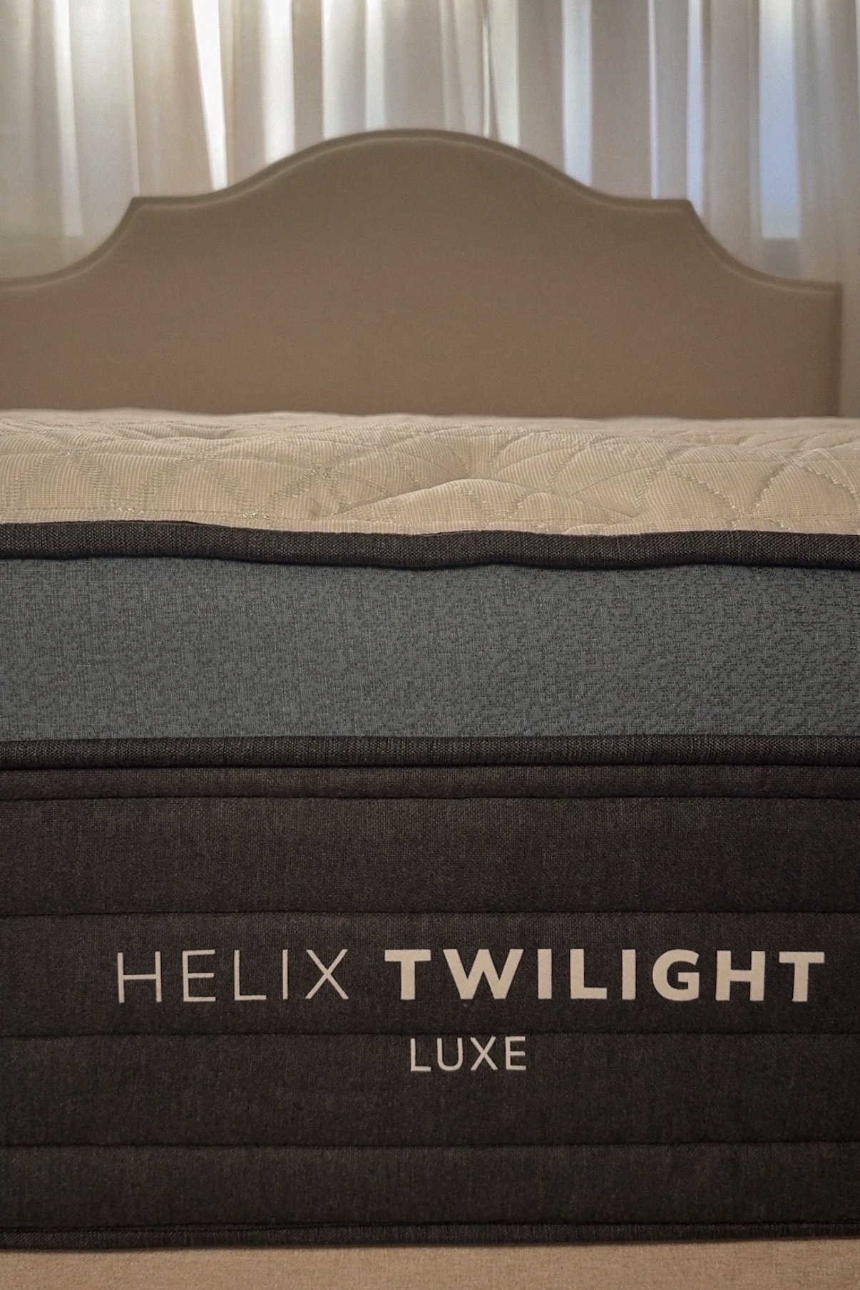 Close-up of the Helix Twilight Luxe mattress thickness and edge support on a wooden bed frame in a neutral bedroom setting.