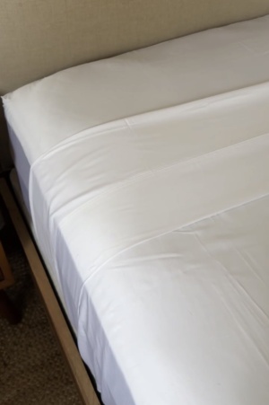 Helix Cool Shift sheets styled on a neutral bed with soft white bedding and layered pillows in a cozy, vintage-inspired bedroom.